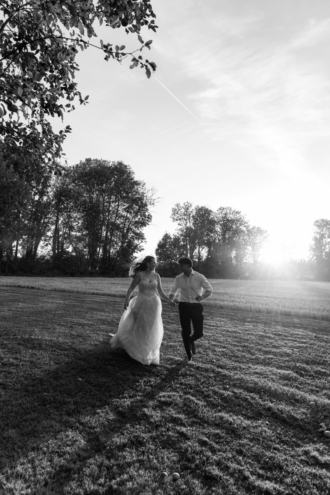 Brautpaar läuft im Gegenlicht über eine Wiese, schwarzweiß — Hochzeitsfotografie NRW